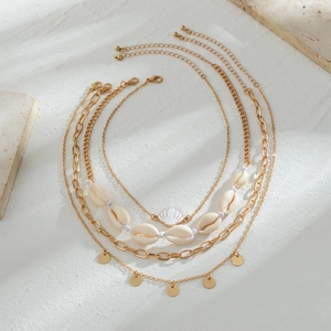 Detail of four-layer gold necklace set with seashells, cowrie charms and paperclip chains