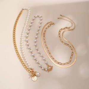 Detail of layered gold link chains and faux pearl necklaces with starfish and coin pendants