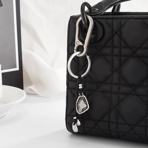 Detailansicht eines grauen Kristall-Taschenanhängers mit silbernem Metallclip an der Tasche