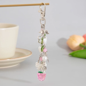 Détail d'un porte-clés fraise rose avec perles, nœud en résine et pendentif d'aile