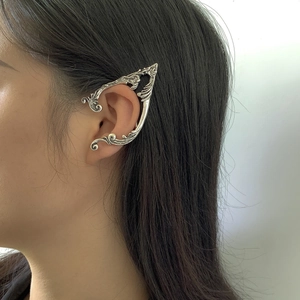 Detailed macro view of vintage silver elf ear cuff with intricate hollow curved patterns