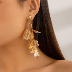 Close-up of layered golden ginkgo leaf earrings with long tassels and a drop pearl bead