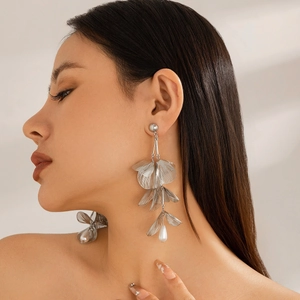 Close-up of silver ginkgo leaf fringe earrings with drop pearl on female model