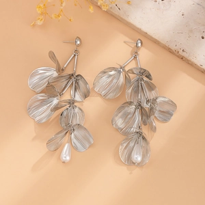 Detail of silver ginkgo leaf earrings with tassels and teardrop pearls on beige background