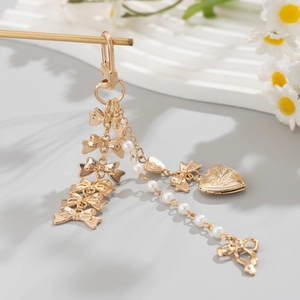 Détail de breloques nœuds dorés, chaîne de perles et pendentif cœur gravé Love you