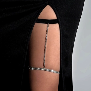 Detail shot of a sparkling rhinestone thigh chain with an elastic band on a dark background