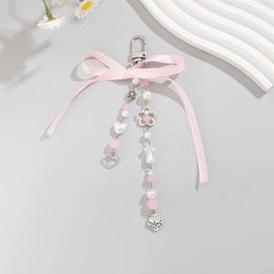 Porte-clés nœud rose avec perles et breloques cœur argentées sur décor blanc