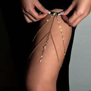 Detail of multi-layer gold leg chain with sparkling crystals on black background