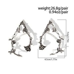 Macro detail of vintage silver elf ear cuffs featuring rose vine and leaf metalwork