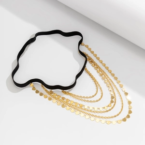 Detail of layered gold leg chain with heart sequins and black elastic thigh band
