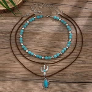 Λεπτομέρεια boho κολιέ με τυρκουάζ χάντρες και μενταγιόν κάκτου σε ξύλινο φόντο