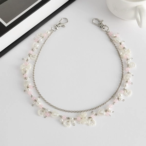 Detail van meerlaagse tailleketting met roze kralen en strikvormige hanger
