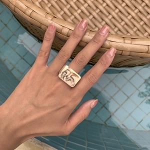 Vue rapprochée d'une bague géométrique en résine crème à texture marbrée