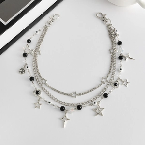 Detail van een gelaagde punkketting met zilveren sterren en zwarte kralen