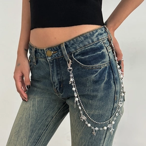 Detail of silver multi-layer waist chain with pearls and stars on denim jeans