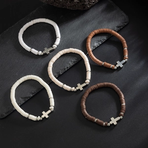 Detailed macro view of heishi bead bracelets with silver cross charms in earth tones