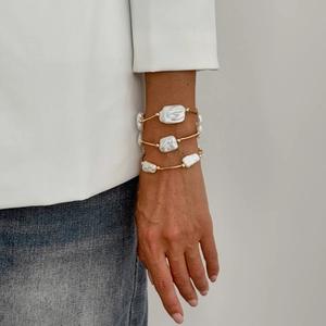Three-piece gold baroque pearl bracelet set worn on wrist for minimalist fashion look
