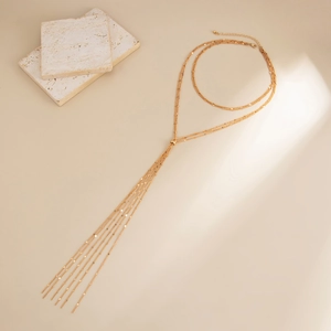 Chic multi-layered Y-shaped gold tassel necklace with metallic sequins on beige background