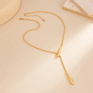 Detail of gold snake chain necklace with teardrop pendants on stone tray display
