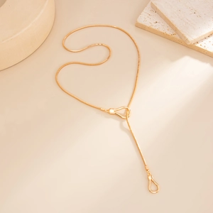 Detail of gold snake chain necklace featuring elegant metal ring toggle clasp and pendant