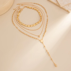 Detail of layered gold-plated necklaces with religious medal and teardrop pendants