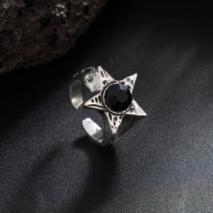 Dettaglio di un anello a stella vintage con gemma nera sfaccettata su sfondo scuro