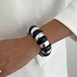 Close-up of a chunky elastic bracelet with silver metal and black marble resin links