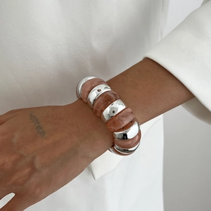 Detail of silver metallic and pink resin chunky bracelet segments on wearer's wrist
