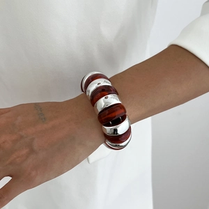 Macro shot of chunky resin and silver metal chain bracelet on a model's wrist