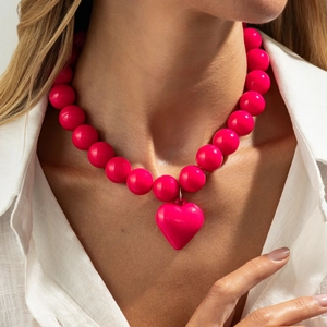 Primer plano detallado del collar de cuentas rosa intenso con colgante de corazón