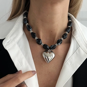 Detalle de collar de moda con colgante de corazón plateado grande y cuentas con efecto mármol