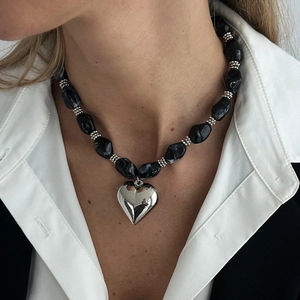 Detalle de un gran colgante de corazón plateado pulido en un collar de cuentas de mármol