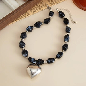 Detalle del collar con colgante de corazón plateado con cuentas de mármol y cadena
