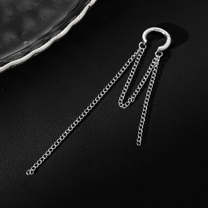 Macro detail of silver C-shaped ear cuff with triple long metal chain fringe on black background