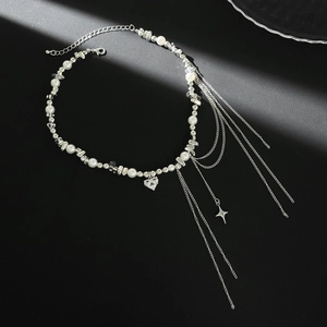 Detail of tassel necklace with heart crystal pendant, faux pearls and star charm details
