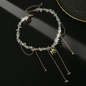 Macro shot of irregular white crystals and golden bird pendant on fringe necklace