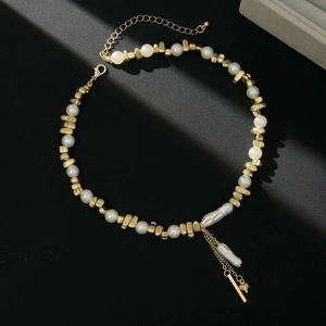 Detailed macro of vintage pearl necklace with gold fringe and heart charm on black