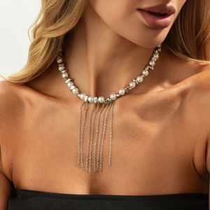 Macro detail of silver tassel chain fringe on pearl necklace worn by a model