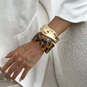 Manchette dorée irrégulière et bracelet nœud en résine léopard sur poignet de mannequin