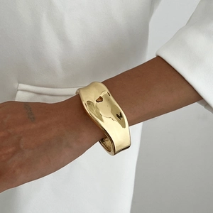 Vue détaillée d'un bracelet manchette irrégulier en métal liquide au fini doré poli