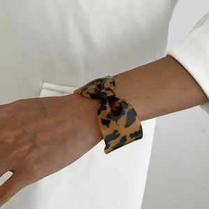 Gros plan d'un bracelet en résine écaille de tortue avec un design de nœud porté par un mannequin