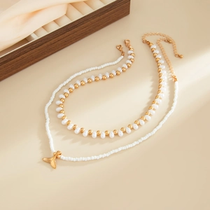 Détail d'un collier multicouche doré avec pendentif queue de poisson et perles baroques