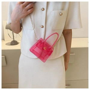 Détail d'un mini sac bandoulière rose transparent en PVC avec une chaîne dorée