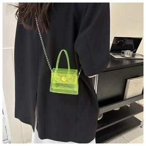 Mini sac à bandoulière transparent vert néon avec chaîne dorée sur une veste noire