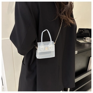 Détail d'un mini sac bandoulière blanc givré avec une chaîne dorée et fermoir rond