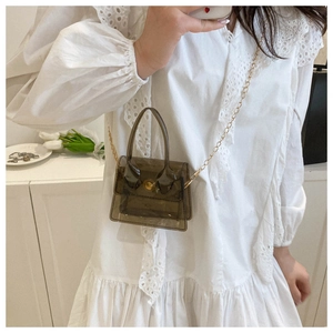 Mini sac en PVC marron translucide avec chaîne dorée et poignée porté par un modèle