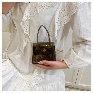 Détail d'un mini sac bandoulière marron transparent en PVC avec chaîne dorée