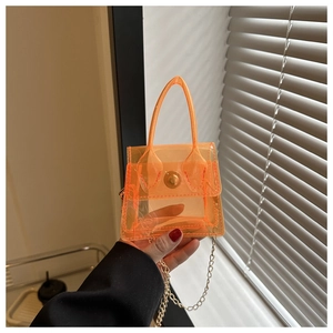 Détail d'un mini-sac transparent orange en PVC avec chaîne dorée et boucle ronde en métal