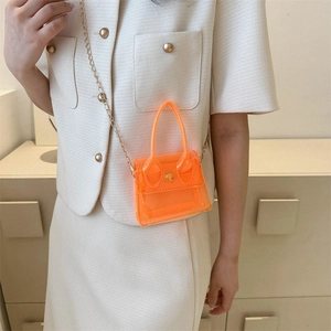 Mini sac bandoulière orange transparent avec chaîne dorée porté sur un mannequin