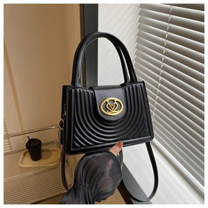 Detail van zwarte leren tas met concentrische stiksels en gouden hartvormige gespsluiting